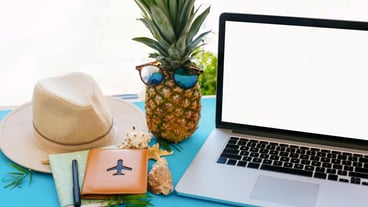 Planning summer vacation concept laptop with empty screen pineapple in sunglasses passport map hat on blue trendy paper with shells space for text travel and wanderlust
