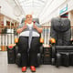 Fat woman with ice cream sitting in a massage chair in mall. Overweight female person poses in a leather armchair in shopping center, obesity problem