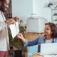 Best option. Charming cheerful young man showing two printouts with project design concepts and the woman choosing one of them