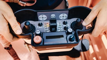 Remote control of a lifting car crane in the hands of a person. A panel with joysticks and buttons for controlling the telescopic bucket of the crane