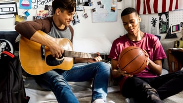 Teenage boys hanging out in a bedroom music and sports hobby concept