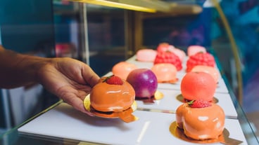 Close up of vendor's hands taking out cake from showcase in bakery