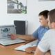 Middle-aged managers discussing business while looking at their website using a laptop at their desk.