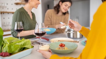 Group of friends eating pasta together in the kitchen
