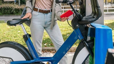 Side view of unrecognizable woman using her smartphone to rent a bicycle from the bike rental station to ride around the city.