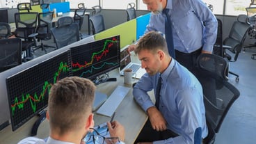 Group of modern business men in formalwear analyzing stock market data while working in the office