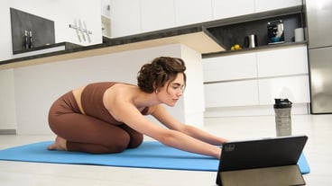 Image of young sportswoman does yoga at home watches gym instructor tutorial video on tablet