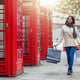 Full length of young woman holding shopping bags while walking on footpath in city