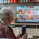 Elderly woman using VR technology while watching TV