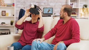 Nephew showing his grandmother how to use virtual reality glasses in the living room.