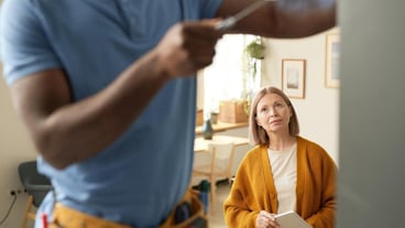 Blonde Senior Woman Watching Man Doing Home Repairs