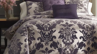 Purple and white bedding in a bedroom with a lamp on the side.