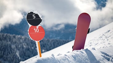 Slope number signs and snowboard standing upright on the edge of ski slope in snow