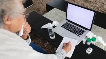 Mixed race senior woman sitting on sofa making video call using laptop