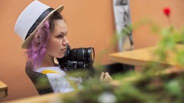 Teenager girl with camera sitting in an city outdoor cafe