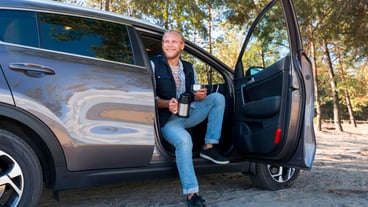 Man drinking coffee and sitting in the car long view