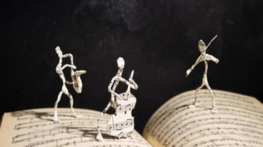 paper figures of jazz musicians stand on an open music notebook
