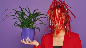 Woman having her face covered in plastic while holding a plant