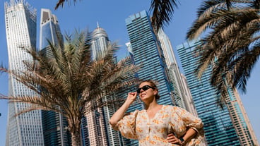 Attractive traveler woman wearing a long dress walking on a promenade in Dubai Marina district Travel destinations and tourist lifestyle in UAE