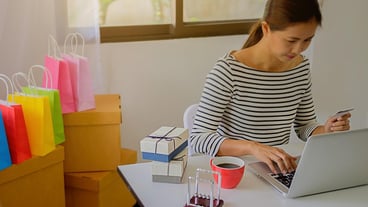 Businesswoman holding credit card while using laptop on table