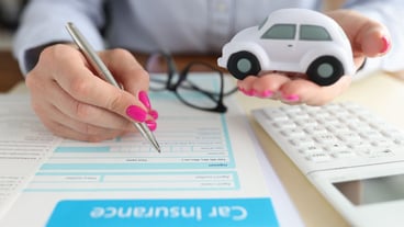 Woman holding toy car in her hands and filling out insurance form closeup