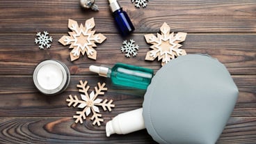 Christmas flat lay with makeup cosmetic products in cosmetic bag on colored background Top view New year Beauty concept