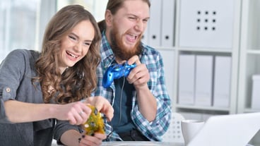 Portrait of a happy young couple with laptop playing game at home