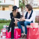 Happy couple sitting with smartphone on bench