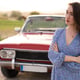 Beautiful girl in retro style posing near vintage red cabriolet car