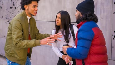 Urban style, three black Latino friends having fun in the street and talking to each other.