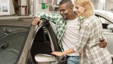 Young couple examining new car at the dealership