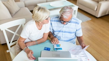 Senior couple smiling checking utility bills or insurance at computer with easy access elderly users of technology