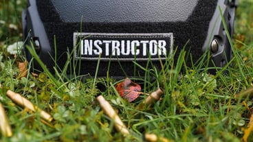 Instructor tactical black helmet with the inscription instructor lies on the grass with rifle shells