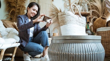 Beautiful girl using a phone while picking up a woven bag in a craft store