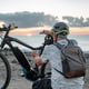 Rear view of active caucasian senior man with electric bicycle at sunset on the beach elderly man with helmet enjoying healthy lifestyle
