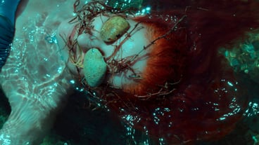 Woman with eyes covered by stones swimming in sea
