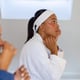 Happy biracial lesbian couple in bathrobes wearing eye masks in bathroom. Lifestyle, beauty, self care, wellbeing, relationship, togetherness and domestic life, unaltered.