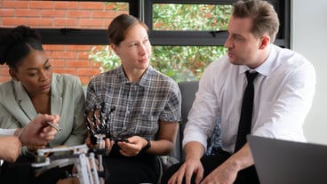 A group of different business people working together in the office and brainstorming about the handheld robot
