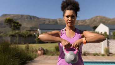 Woman exercising with kettlebell in the backyard of home