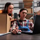 Warehouse shipment managers reading delivery customer satisfaction on laptop. Retail storehouse asian man and woman employees checking pick ticket and preparing box for dispatching