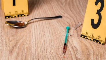 A drug syringe next to a police sign on the floor of the house. The concept of crime.