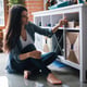 Woman sitting next to a shelf indoors