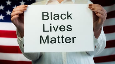 Woman holds poster Black Lives Matter on american flag background