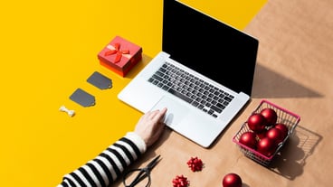 Laptop computer with female hand and Christmas gifts, objects for wrapping
