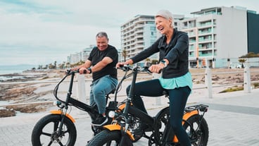 Senior couple electric bike and smile by the beach for fun bonding cycling or travel together in the city Happy elderly man and woman enjoying cruise on electrical bicycle for trip in Cape Town
