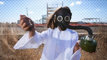 Portrait of girl wearing gas mask while standing by fence