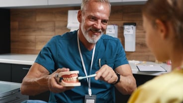 Smiling Dentist Showing Dental Model to Patient
