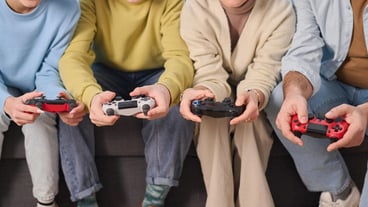 Closeup of family of four using joysticks to play game console together at home