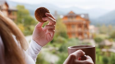 Woman holds cup of coffee and oat cookie in her hands at mountain resort female with tea mug and