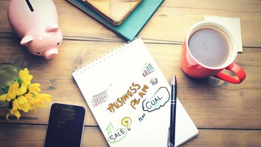 Office table with a coffee cup, a plan on notepad